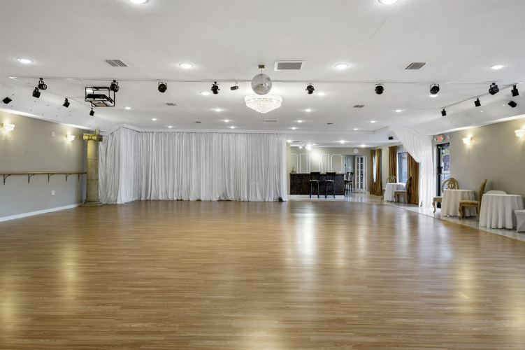 blank canvas ballroom space with bar, hardwood floors and cream colored walls