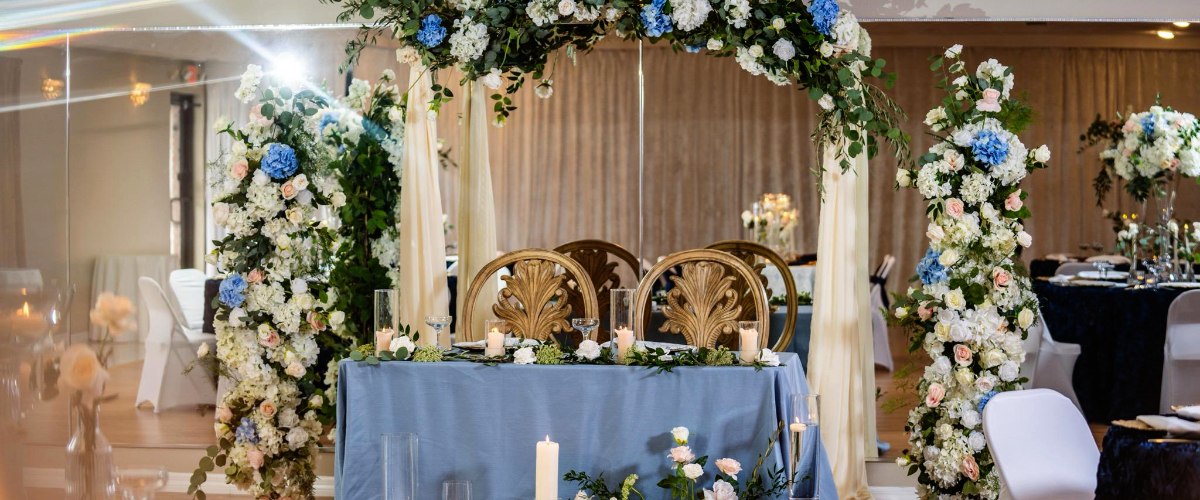 stunning head table with lilac blue table cloth and arched flowers with blue shades ivory and gold accents